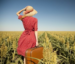 Redhead girl with suitcase at corn field.